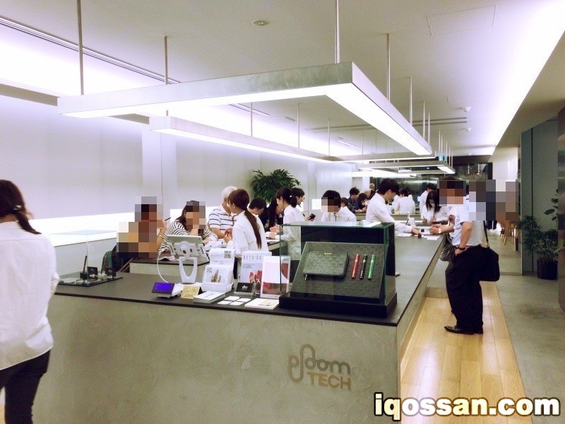 正在说明Ploom TECH的工作人员与听取说明的顾客。也有人正在吸烟。